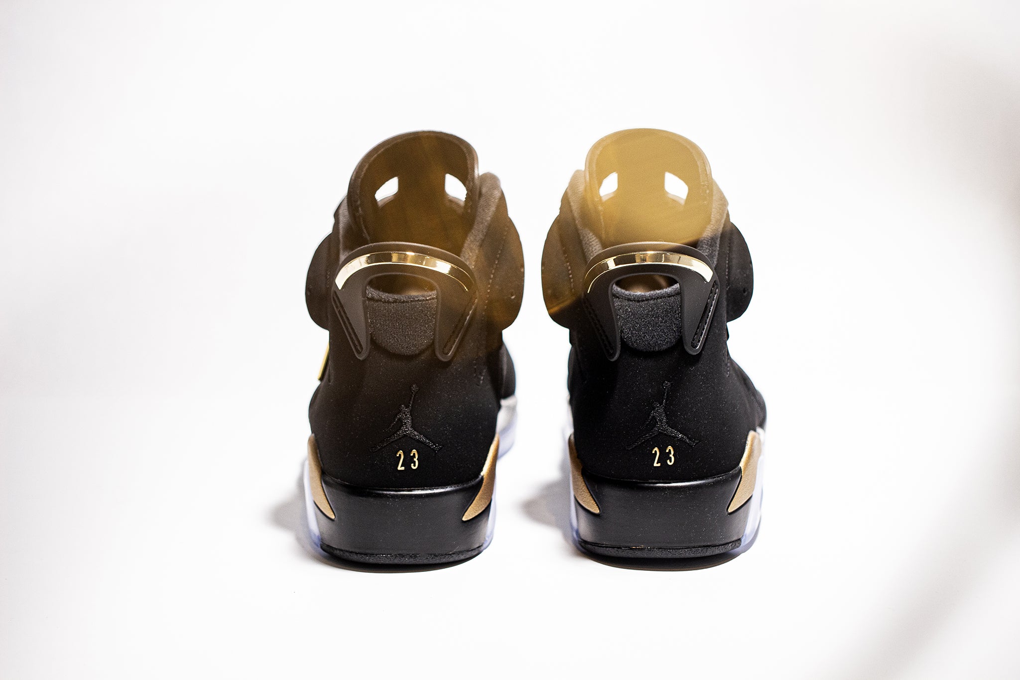 Reverse side view of a pair of black gold Jordan 6 sneakers