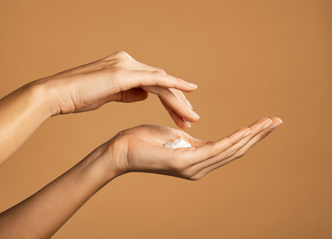 A person rubbing CBD lotion into their hands to soothe the skin