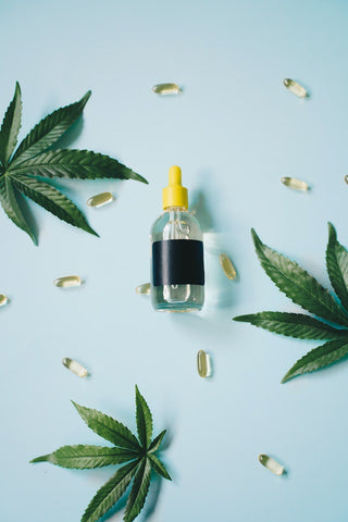 A bottle of CBD oil neatly positioned on a table with hemp leaves and CBD oil capsules.