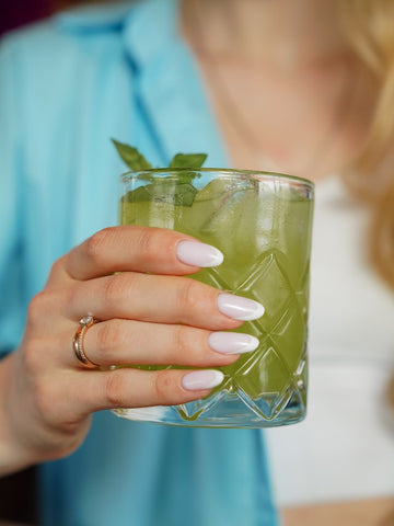 A woman holding a cocktail, which should be combined cautiously with THC products. 