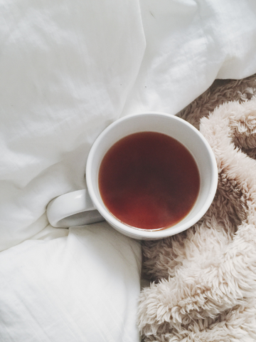 A cup of lion's mane tea sitting near a cozy blanket