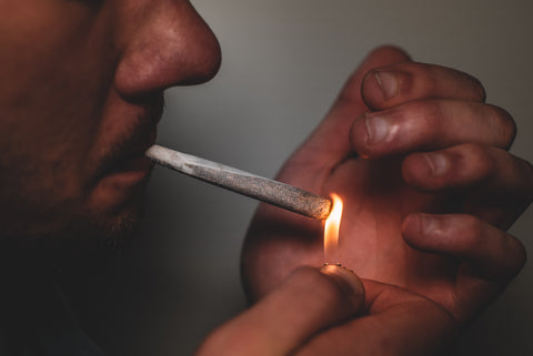 Man lighting hand-rolled herbal joint
