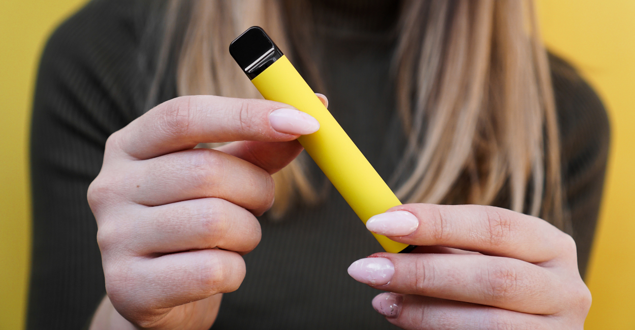 A woman holding a yellow disposable Delta-11-THC vape