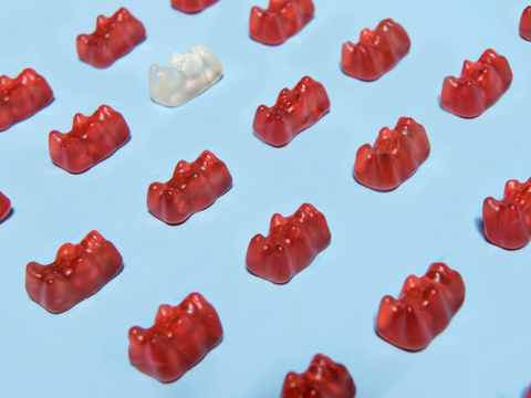 Rows of red and white CBD gummy bears positioned neatly against a blue background