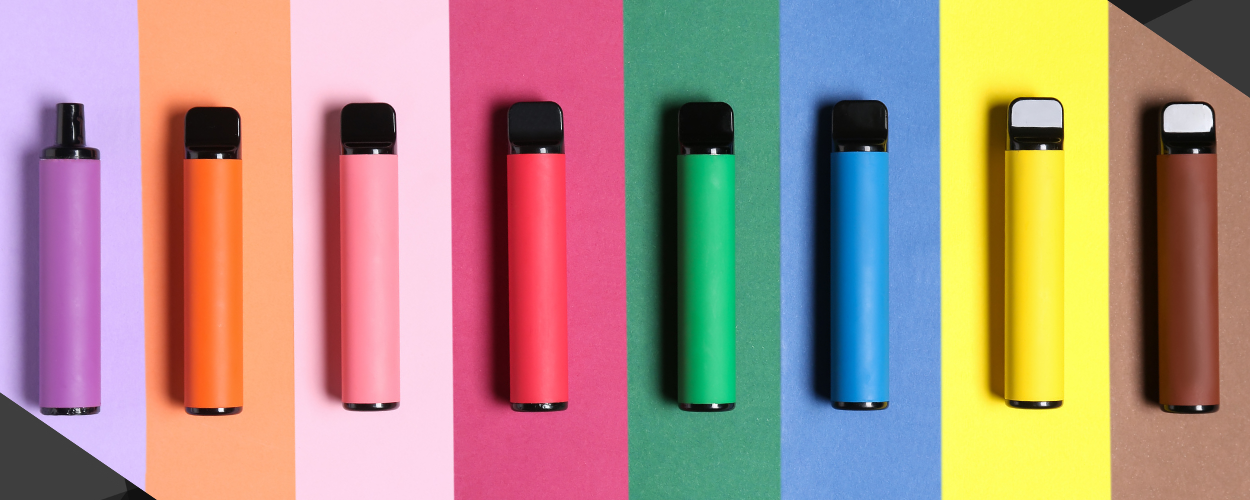 A selection of multicolored cannabis vape pens arranged in a row on a contrasting background