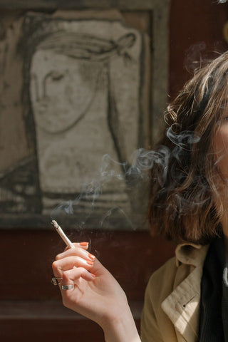 A woman smoking a hand-rolled lavender joint rolled in smoking papers.