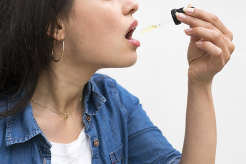 A woman taking a sublingual CBD isolate dose.