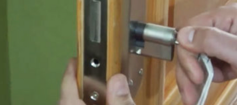 Mano de cerrajero extrayendo el bombín de una puerta
