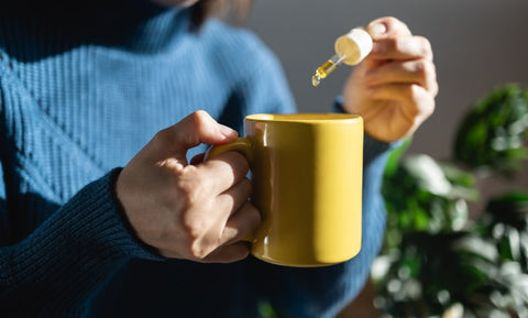 CBD oil being poured into a mug of tea