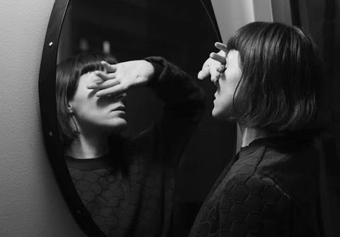 A woman looking at her reflection in the mirror.