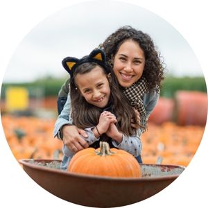 Mom and Daughter with a Pumpkin in a Wheelbarrow at a Pumpkin Patch