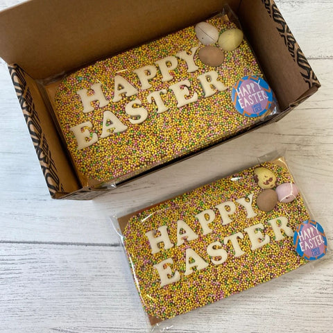handmade chocolate bar with yellow and pink sprinkles, three mini eggs and the words Happy Easter in white chocolate letters