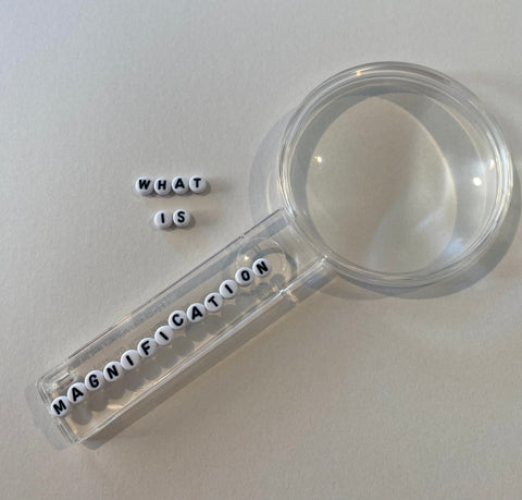 Eschenbach magnifier with small beads in black and white spelling 'what is magnification'