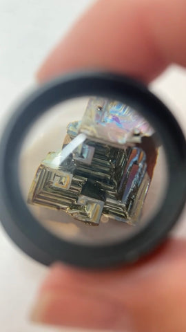 Small stone magnifier, magnifying a detailed piece of metal