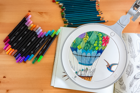 Omega 7 magnifying lamp, showing a colouring book with a hot air-ballon drawing