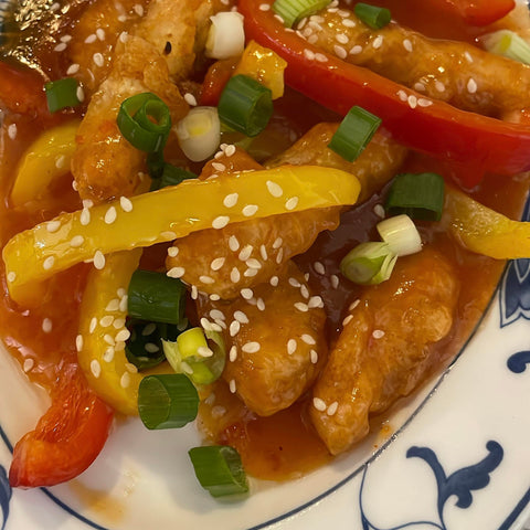 Cooked gluten free cripsy turkey presented on a Chinese plate covered in sesame seeds and spring onions