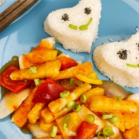 Vegan sweet chilli chicken meal served on a blue plate cooked with spring onions, red peppers and boiled rice