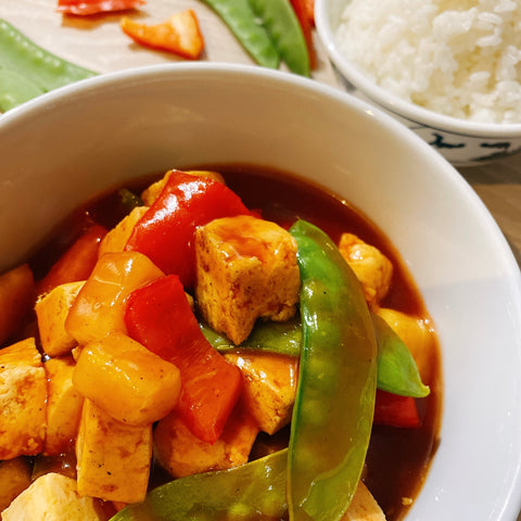 Tofu served in a bowl with mangetout, pineapple, red peppers mixed with gluten free sweet and sour sauce