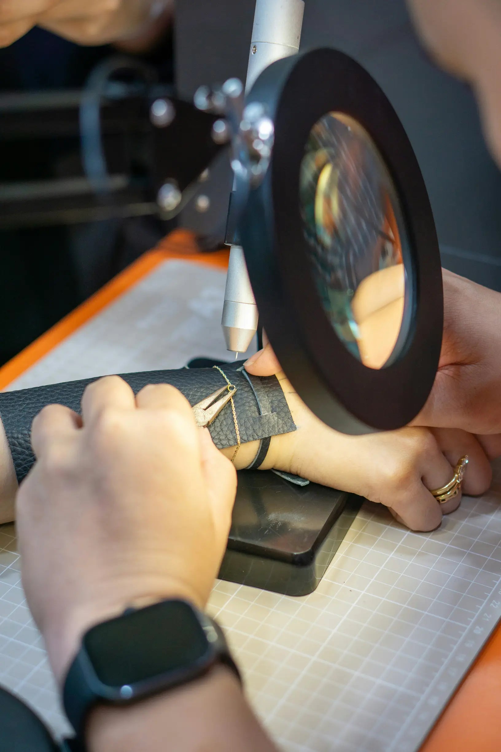 Jeweler using tools and a magnifier to fix a bracelet.