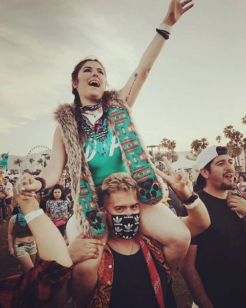 woman on man's shoulders wearing faux fur hood with hand in the air