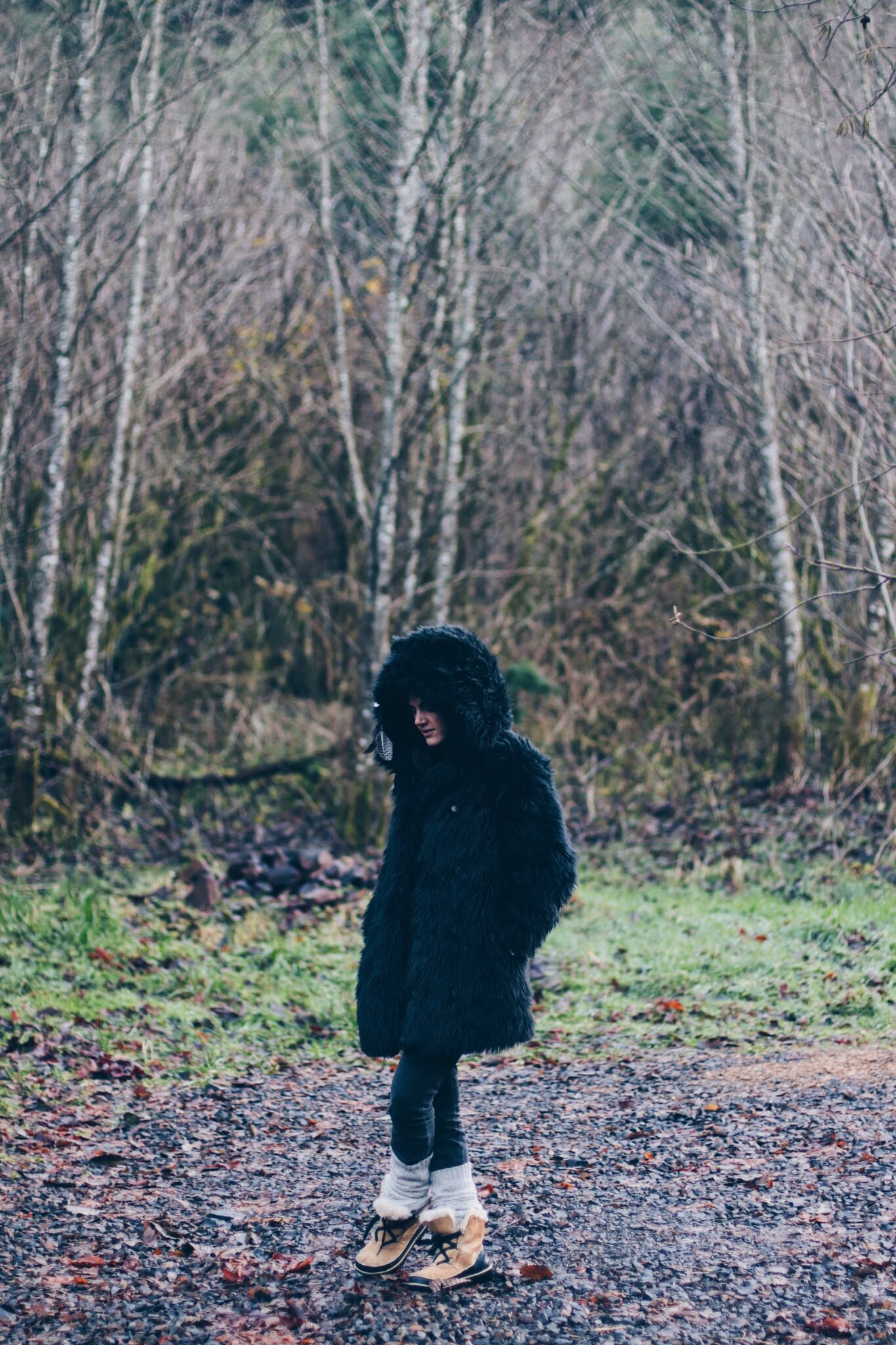 person standing outside in black faux fur coat with hood on