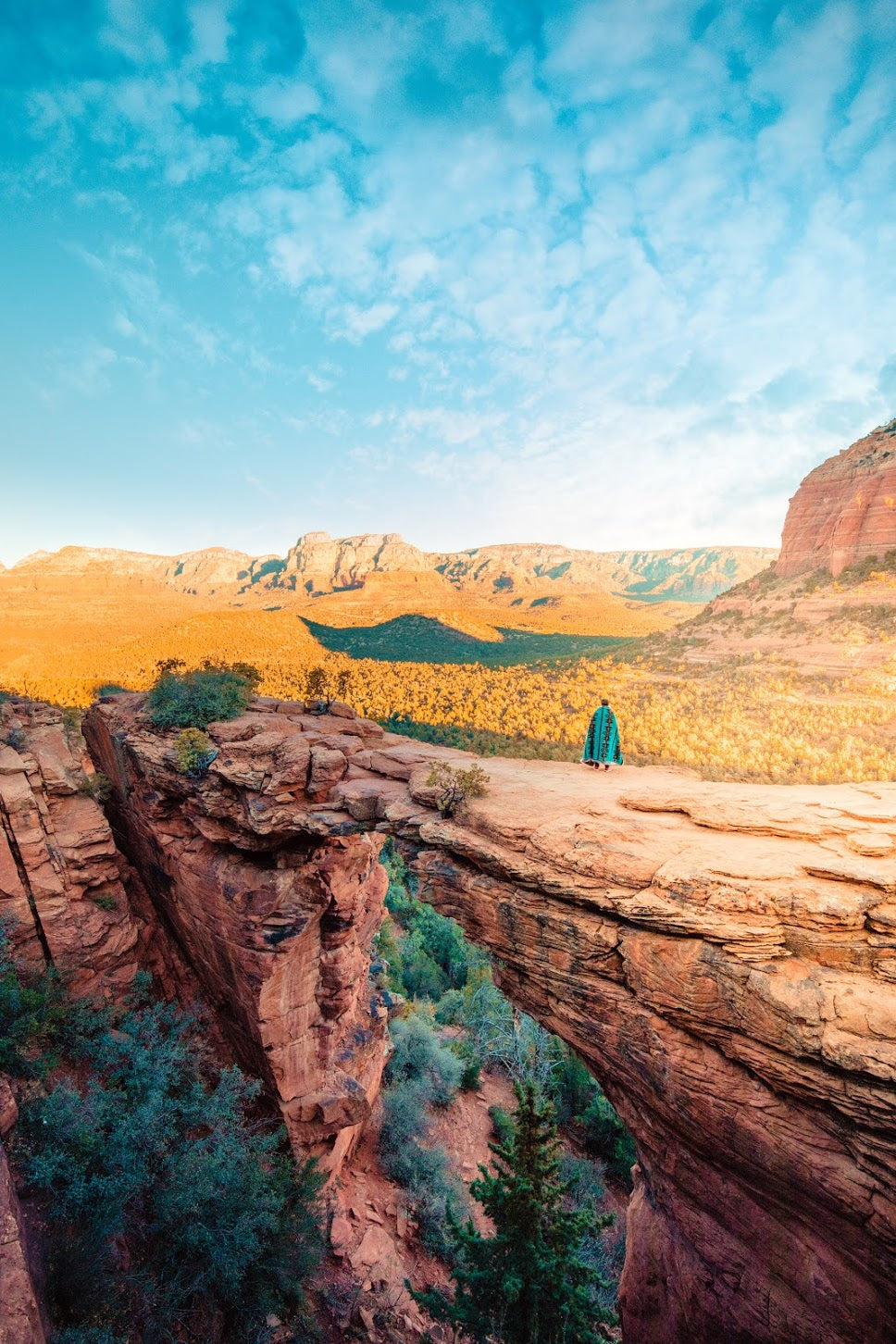 person wearing spirithoods faux fur throw standing on cliff in distance