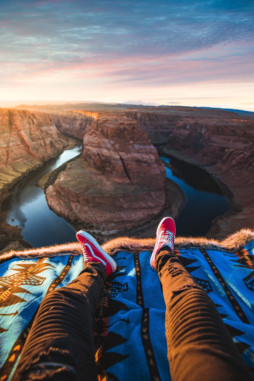 person sitting on cliff on spirithood faux fur throw overlooking scenery