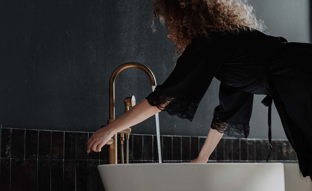 Woman turning knob for bath tub water