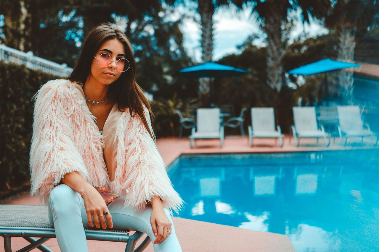 woman wearing jeans and faux fur coat with sunglasses sitting down