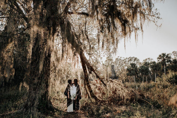 two people in white in forest wrapped in faux fur