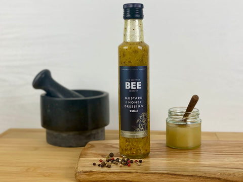 mustard and honey dressing with honey jar on wooden board with pestle and mortar in the background