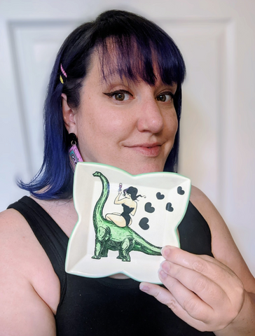 Artist holds a piece she made with a dinosaur on it