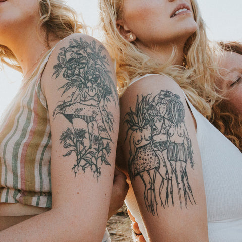 Two people with black ink tattoos of Marcy Ellis's artwork a mix of plants and women