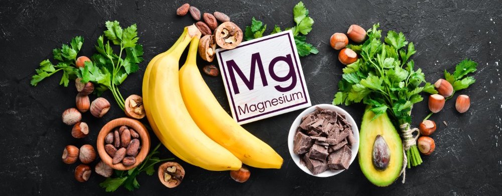 Aliments contenant du magnésium naturel. Mg : Chocolat, banane, cacao, noix, avocats, brocoli, amandes. Vue de dessus. Sur fond noir.