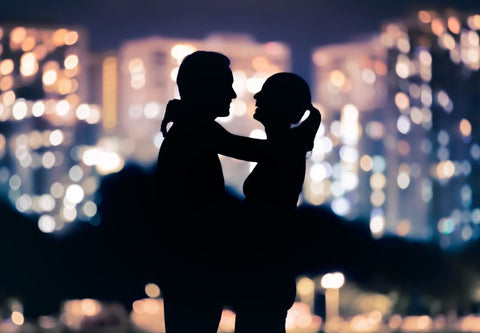 romantic silhouette of man and woman against the night skyline