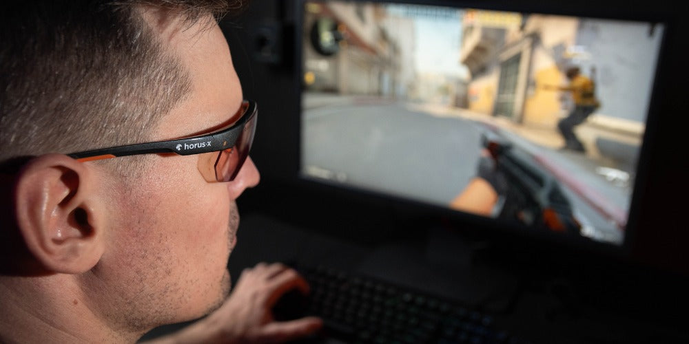 homme portant des lunettes anti-lumière bleue tout en jouant sur un ordinateur