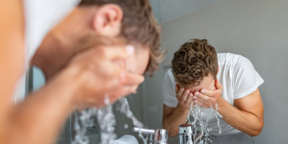 Homme se lavant le visage avec du savon pour le visage dans le lavabo de la salle de bain.