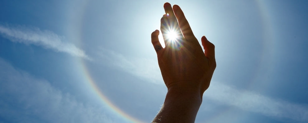 Main de femme couvrant le soleil dans le ciel