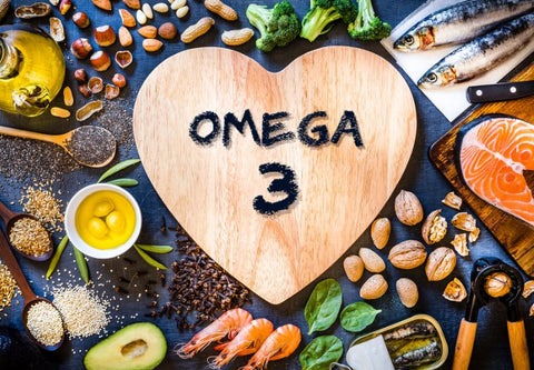 Ein Holzherz mit dem Text Omega 3, umgeben von Produkten, die reich an Omega 3 sind