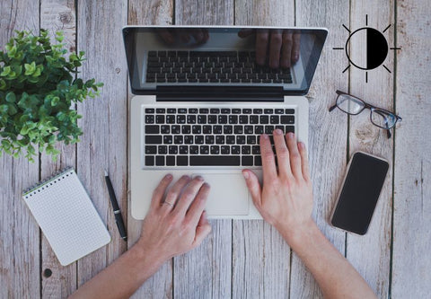 zoom sur les mains d'une personne qui tape sur son macbook, plan de travail épuré avec une plante