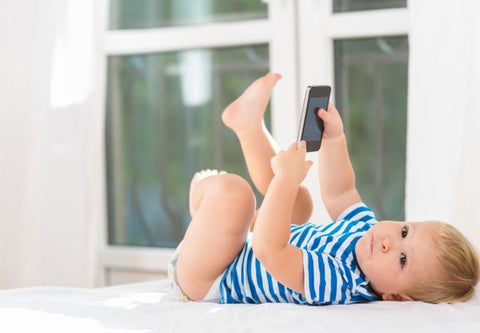 Un bébé sur le dos en train de regarder un téléphone portable