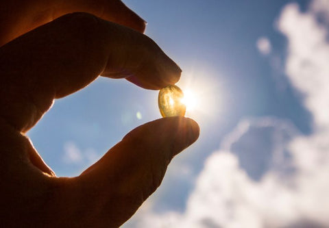 Vitamin-D-Kapsel vor dem Himmel und der Sonne