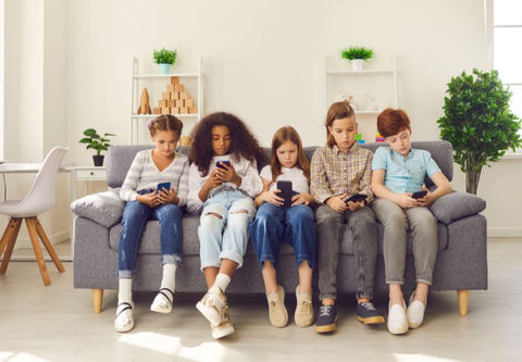 eine Gruppe Kinder auf einem Sofa auf ihrem Smartphone