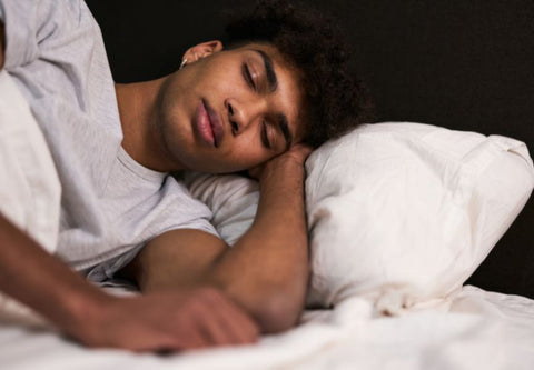 Young man sleeping soundly on his side on a white cushion