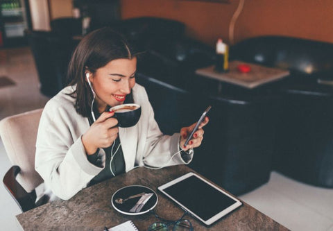 Eine junge Frau trinkt ihren Kaffee vor ihrem Computerbildschirm