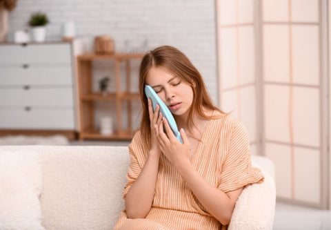 une femme applique une compresse chaude sur son visage