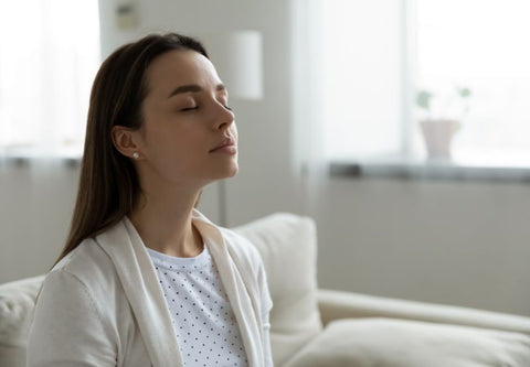 junge Frau auf ihrem Sofa im minimalistischen Dekor mit geschlossenen Augen