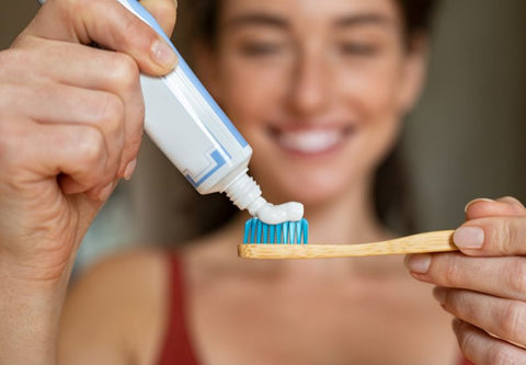 femme qui met du dentifrice sur une brosse à dent