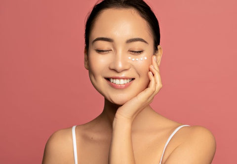 Young woman with glowing skin on pink background