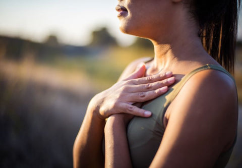 femme avec les mains sur le torse qui respire à plein poumons